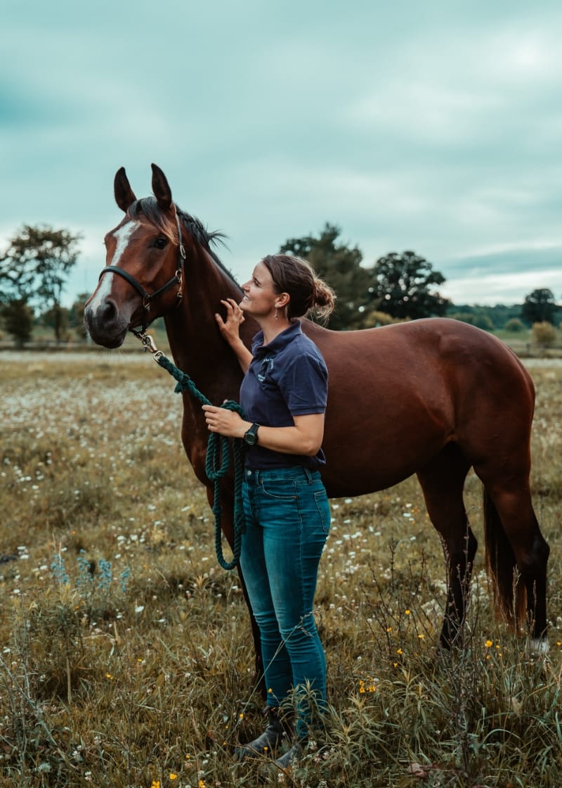 Bronwyn Wearring stands beside a horse and gazes up at its face while the horse looks at something in front of it.