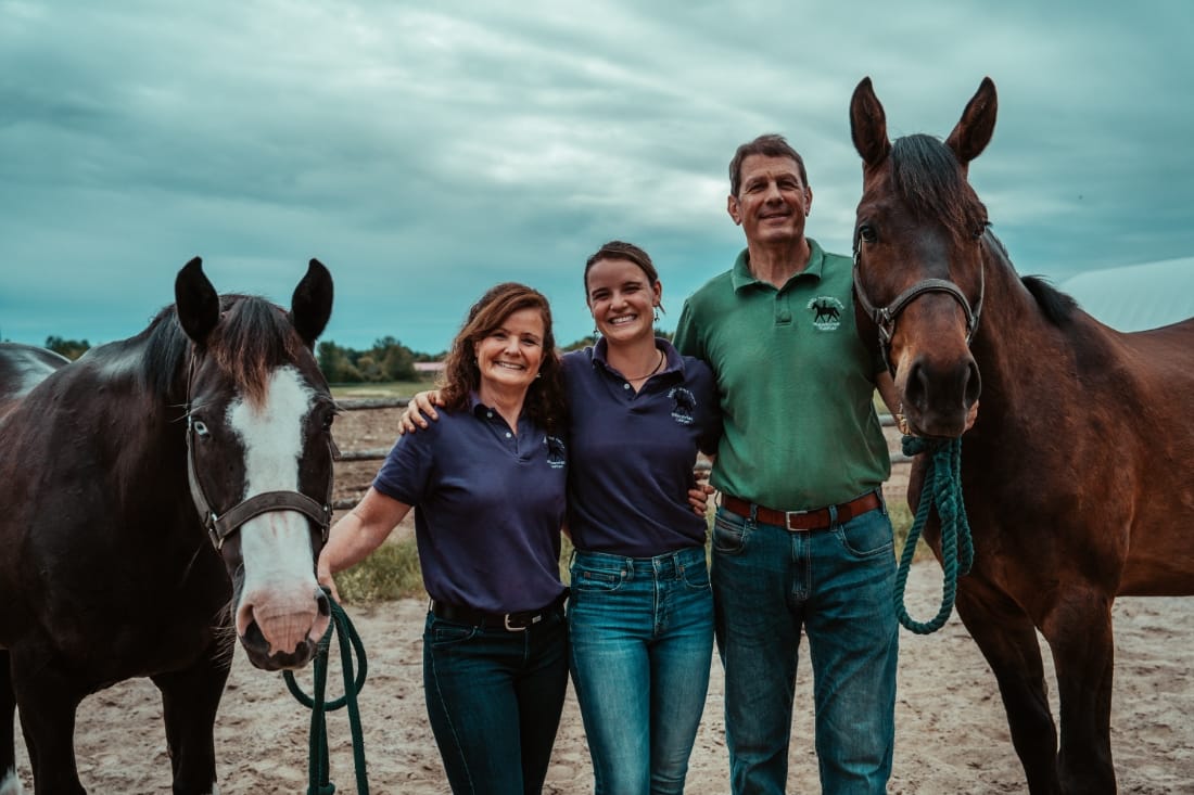 Kate, Bronwyn, and Matt Wearring pose with a horse flanking both sides of the picture.