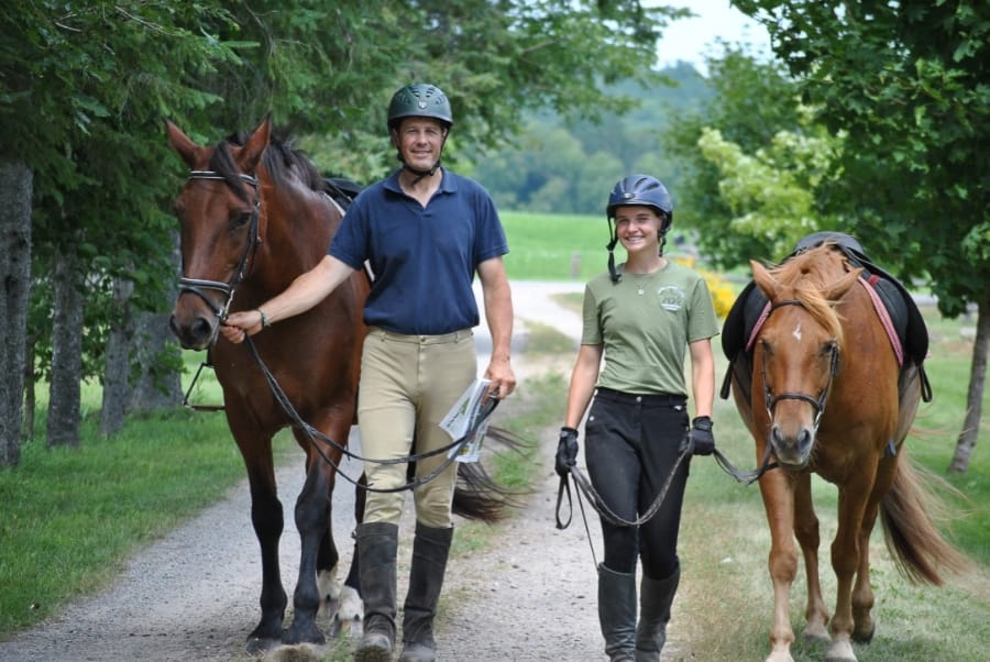 Matt Wearring and Bronwyn Wearring walk toward the camera, each leading a horse beside them.